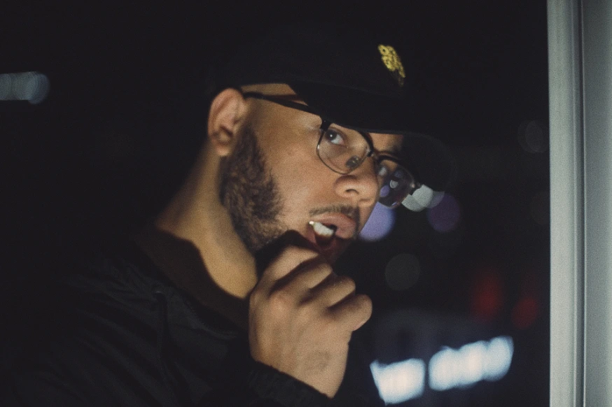 16os in a black cap and glasses at night